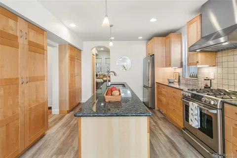 a kitchen with stainless steel appliances granite countertop a refrigerator a stove and a sink with wooden floor