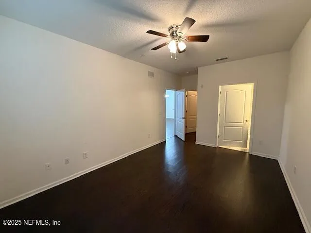 an empty room with wooden floor and ceiling fan