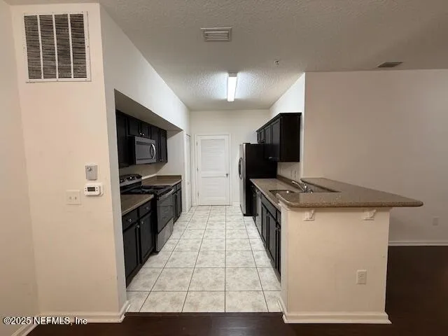 a kitchen with stainless steel appliances a stove refrigerator and a microwave
