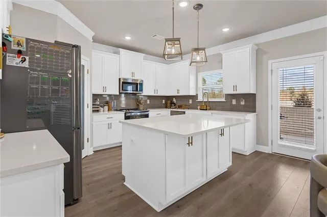 a kitchen with kitchen island granite countertop a sink a counter space appliances and cabinets