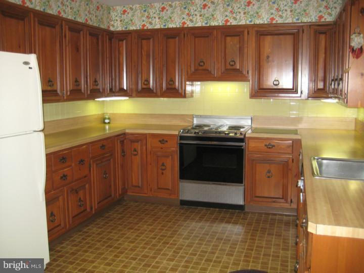 110 Glenwood Road Haddonfield, NJ 08033 - Photo 7 of 17 a kitchen with stainless steel appliances a stove a sink and a refrigerator with wooden cabinets