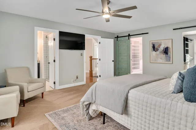 a bedroom with a bed couches and a flat screen tv