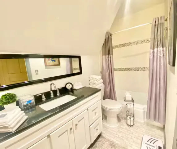 a bathroom with a granite countertop sink mirror vanity and toilet
