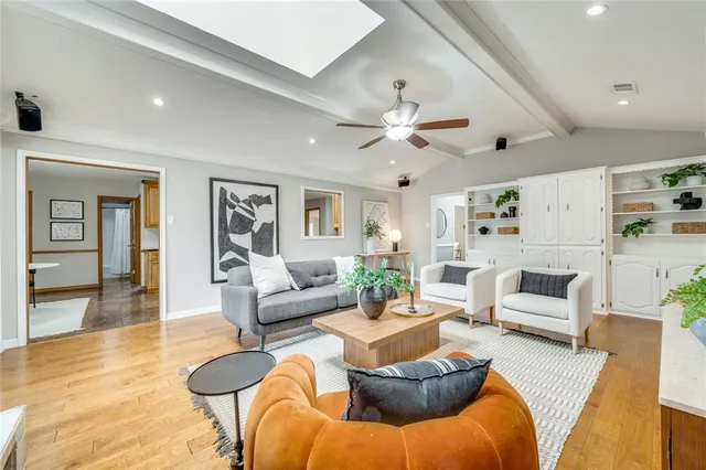 a living room with furniture kitchen view and a wooden floor
