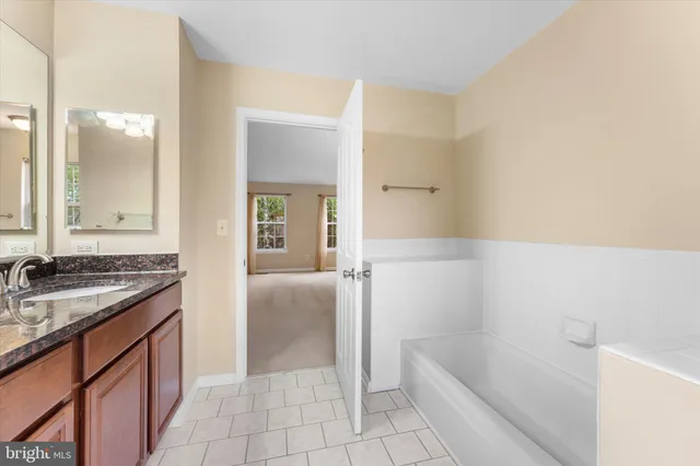 a bathroom with a granite countertop sink a mirror and a bathtub
