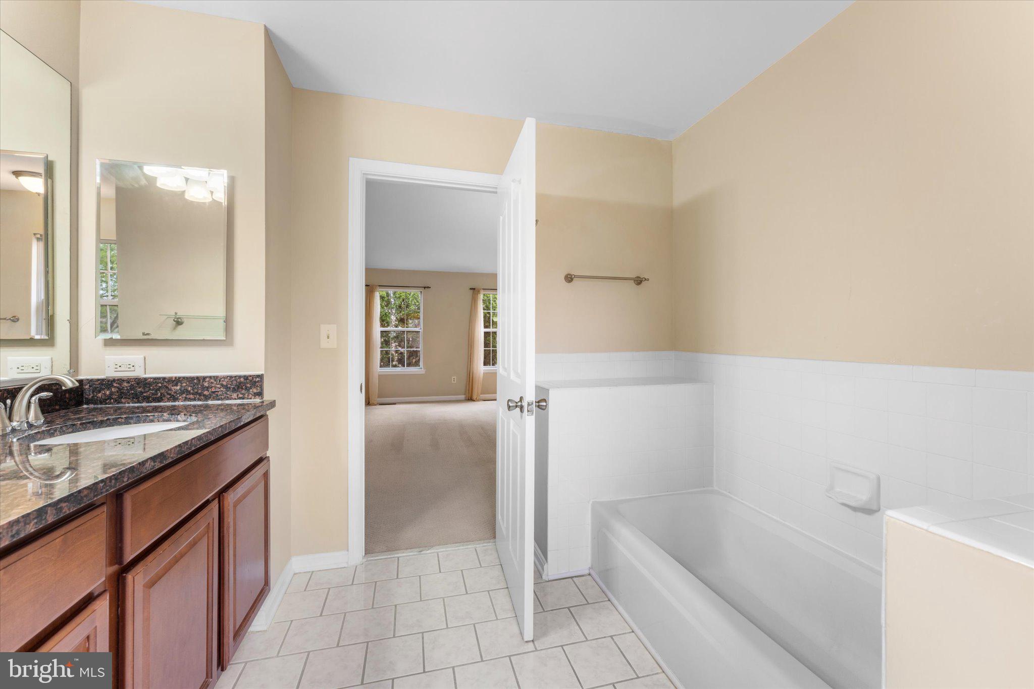 10140 Forest Hill Circle Manassas, VA 20110 - Photo 21 of 42 a bathroom with a granite countertop sink a mirror and a bathtub