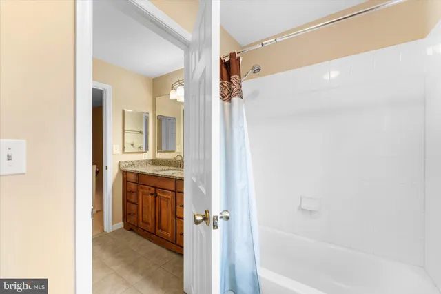 a bathroom with a granite countertop sink a mirror and a bathtub