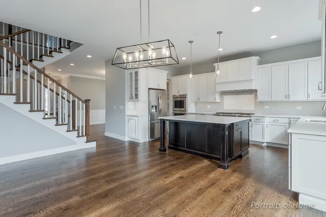 a kitchen with kitchen island stainless steel appliances a table chairs in it and wooden floors