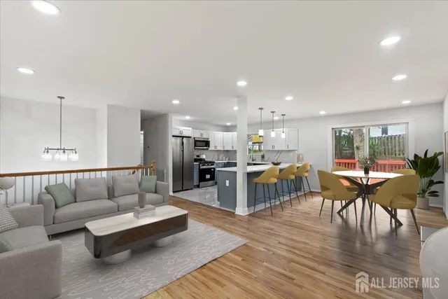 a living room with furniture kitchen view and a wooden floor