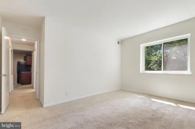 a view of an empty room and a kitchen