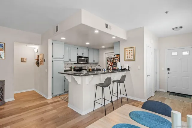 a kitchen with stainless steel appliances kitchen island granite countertop a refrigerator a stove a sink a dining table and chairs with wooden floor