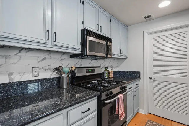 a kitchen with granite countertop cabinets stainless steel appliances and a counter space