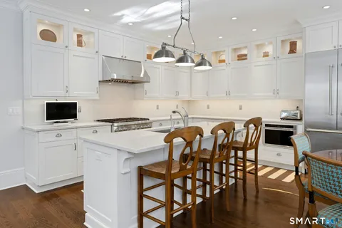 a kitchen with stainless steel appliances granite countertop a table chairs sink and cabinets