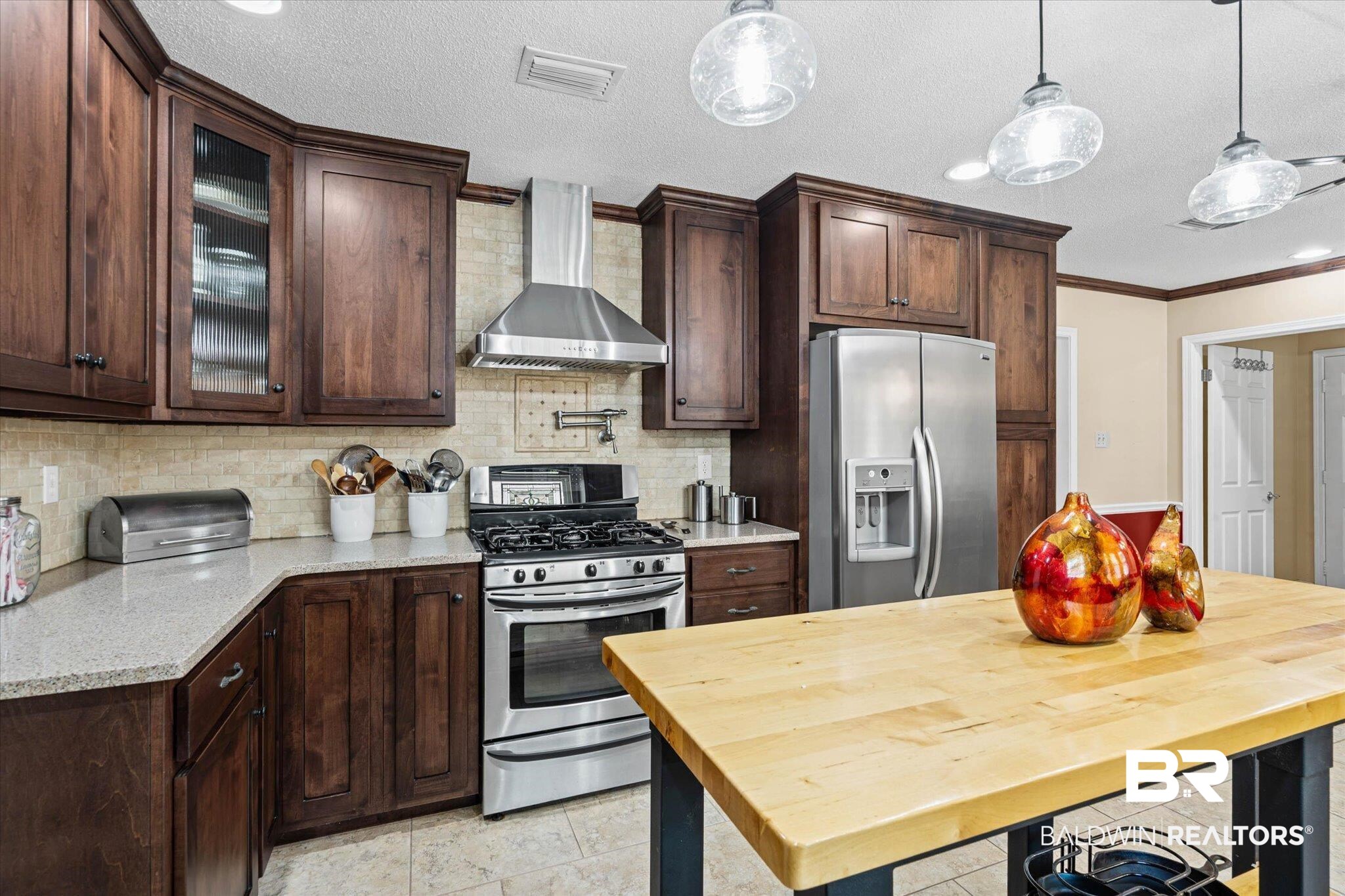 7410 Smithfield Road East Mobile, AL 36695 - Photo 10 of 24 Spacious kitchen featuring rich wood cabinetry, stainless steel appliances, light-toned countertops, tile backsplash, and a central wood-top island