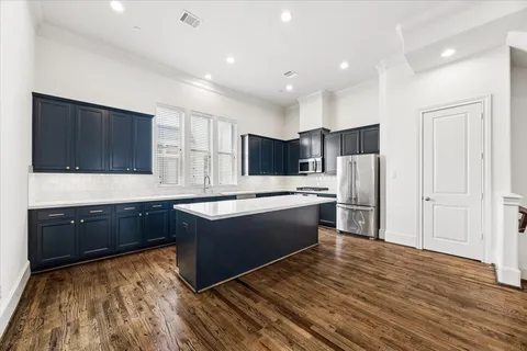 a large kitchen with stainless steel appliances kitchen island granite countertop a refrigerator and a stove top oven