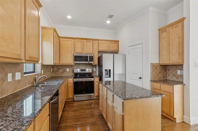 a kitchen with stainless steel appliances granite countertop a stove a sink and a refrigerator
