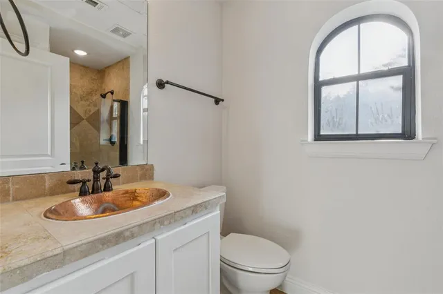 a bathroom with a granite countertop sink a toilet and a mirror