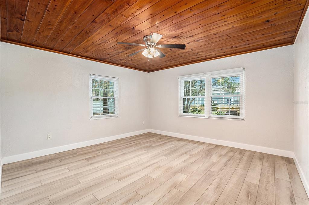 5305 Whiteway Drive Temple Terrace, FL 33617 - Photo 15 of 22 an empty room with wooden floor chandelier fan and windows