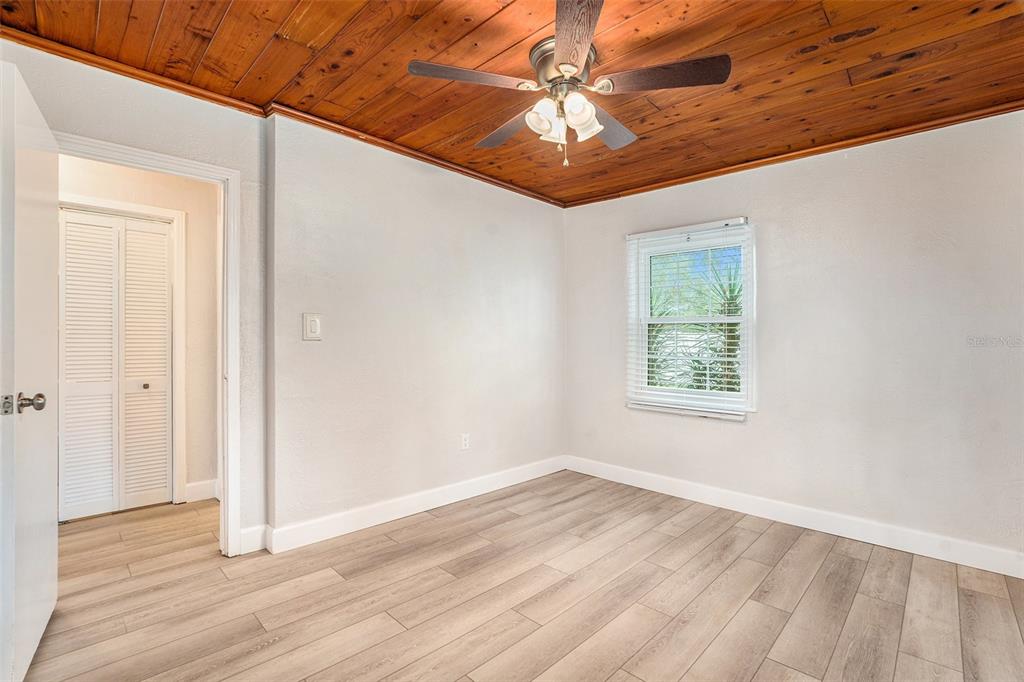 5305 Whiteway Drive Temple Terrace, FL 33617 - Photo 18 of 22 an empty room with wooden floor chandelier fan and windows