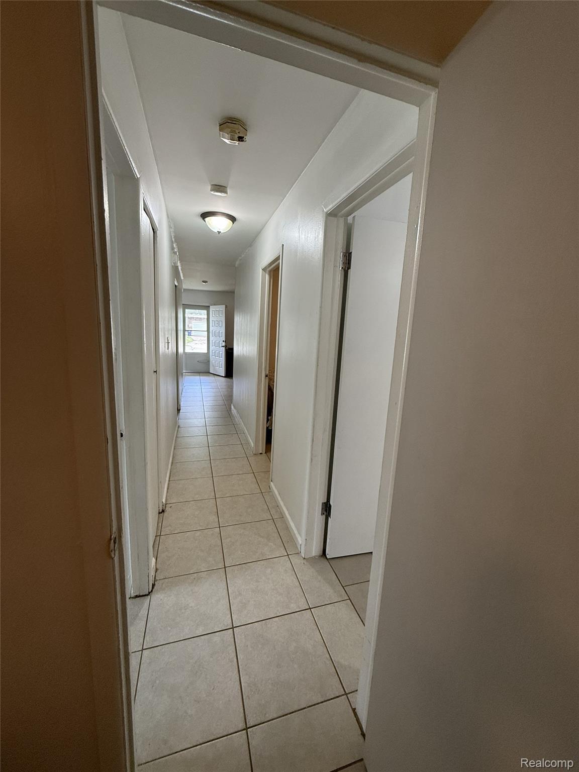 8412 Stephens Road Warren, MI 48089 - Photo 12 of 17 Hallway featuring light-toned square tile flooring, white walls, multiple doorway openings, and a ceiling-mounted light fixture