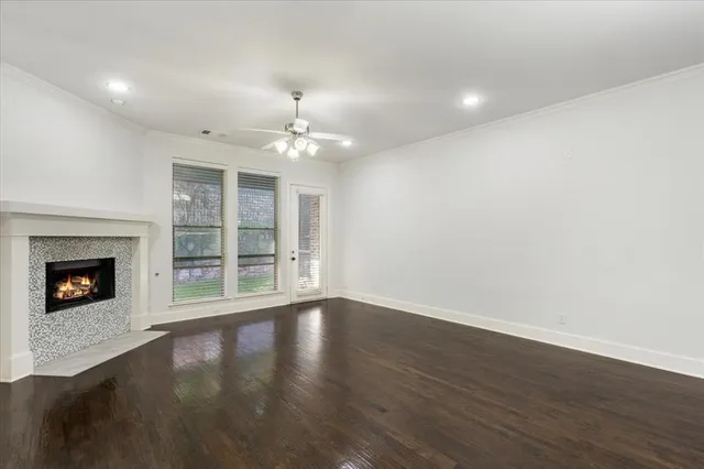 a view of an empty room with wooden floor fireplace and a window