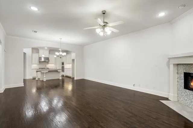a view of an empty room with wooden floor and a kitchen