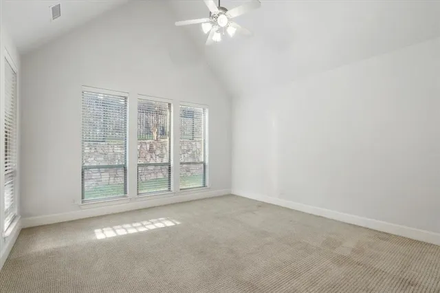 an empty room with windows and ceiling fan