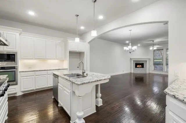 a kitchen with a sink chandelier and cabinets