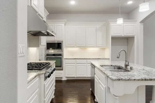a kitchen with granite countertop a sink stainless steel appliances and cabinets