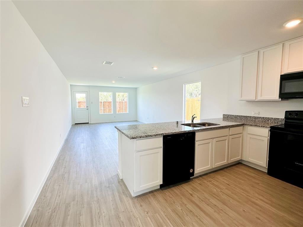 6206 Sanderling Street Princeton, TX 75407 - Photo 15 of 15 a kitchen with granite countertop a stove a sink and white cabinets with wooden floor
