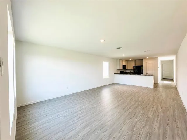 a kitchen with granite countertop a stove a sink and white cabinets with wooden floor