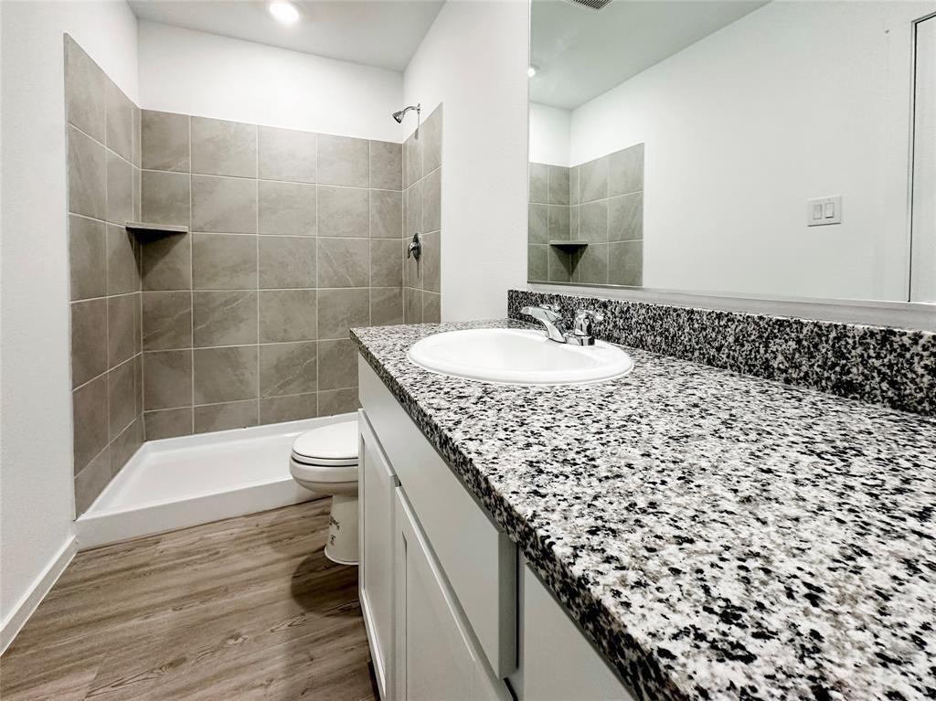 6206 Sanderling Street Princeton, TX 75407 - Photo 7 of 15 a bathroom with a granite countertop shower a toilet and a sink