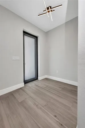 a view of an empty room with wooden floor and a ceiling fan
