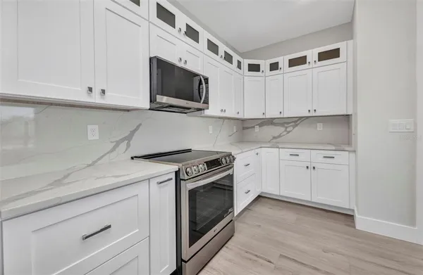 a kitchen with white cabinets stainless steel appliances and wooden floor