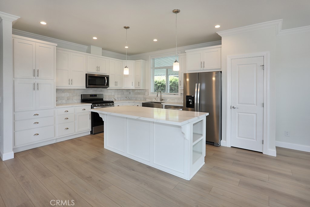 129 La Ronda Tustin, CA 92780 - Photo 4 of 33 a large kitchen with stainless steel appliances granite countertop a stove top oven a sink a refrigerator and white cabinets