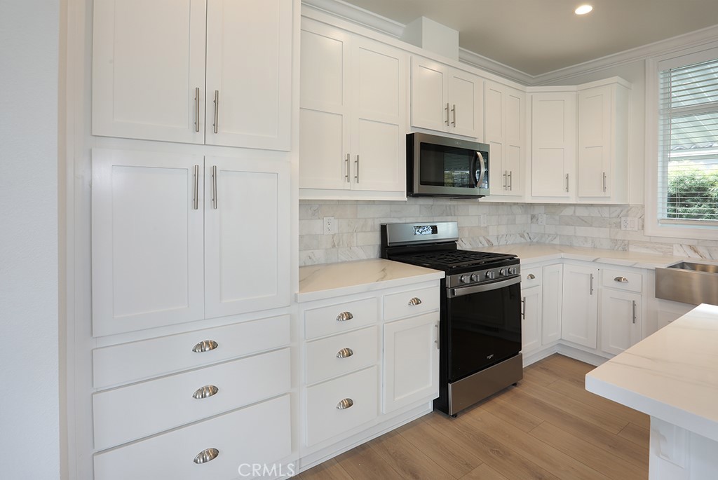 129 La Ronda Tustin, CA 92780 - Photo 6 of 33 a kitchen with white cabinets and black appliances