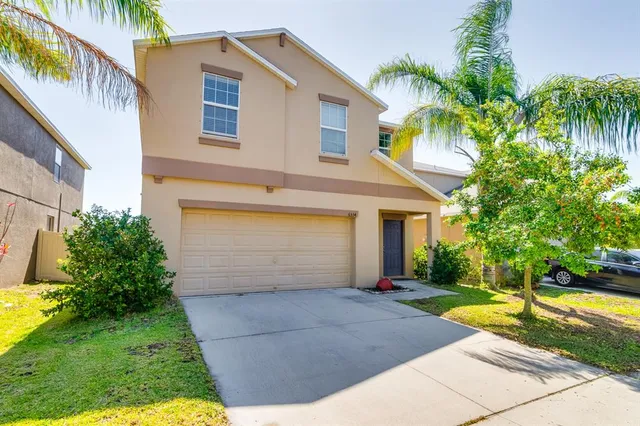 a view of a white house with a small yard plants and palm trees