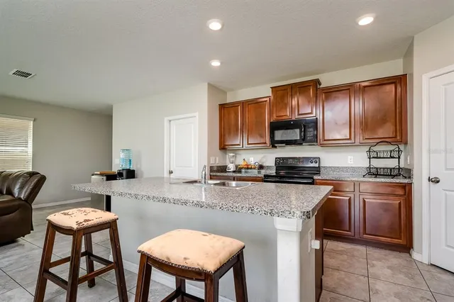 a kitchen with stainless steel appliances granite countertop a stove top oven a sink dishwasher and a refrigerator with wooden cabinets