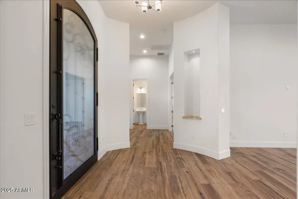 a view of a hallway with wooden floor and a bathroom