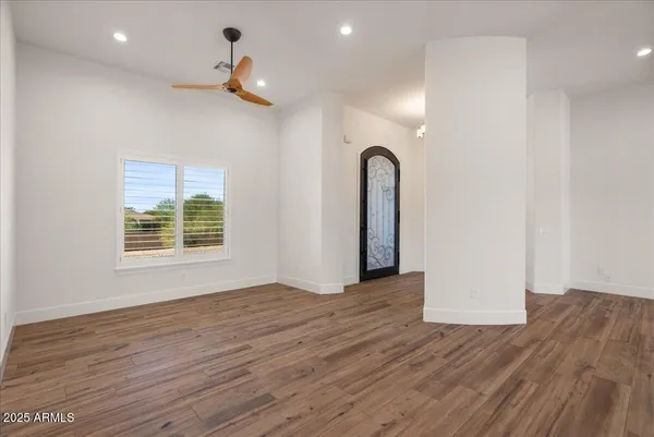 a view of an empty room with wooden floor and a window