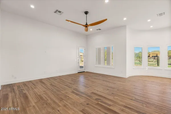 a view of an empty room with a window and wooden floor