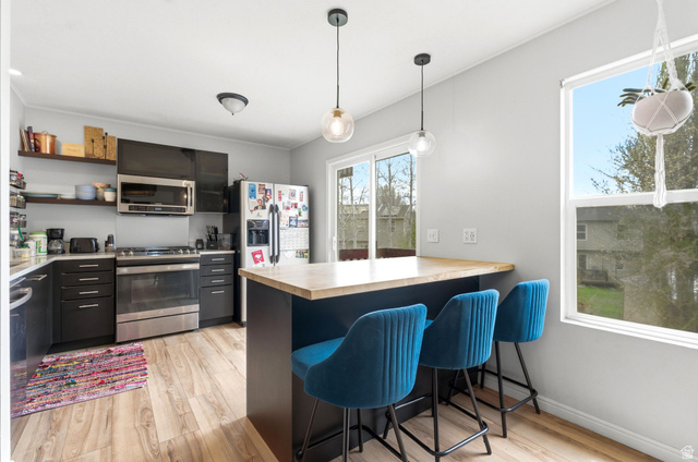 515 Inverness Lane, Unit 207 Heber City, UT 84032 - Photo 7 of 26 Kitchen featuring a kitchen breakfast bar, stainless steel appliances, light wood-style flooring, and decorative light fixtures
