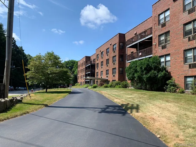 a view of a tall building with a big yard and large trees