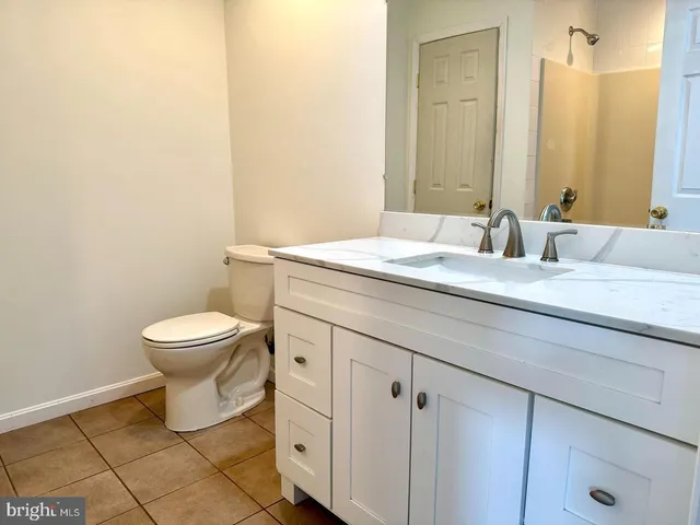 a bathroom with a granite countertop toilet sink and mirror