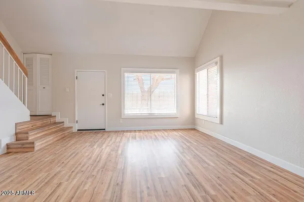 a view of an empty room with wooden floor and a window