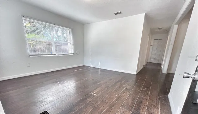 an empty room with wooden floor and windows