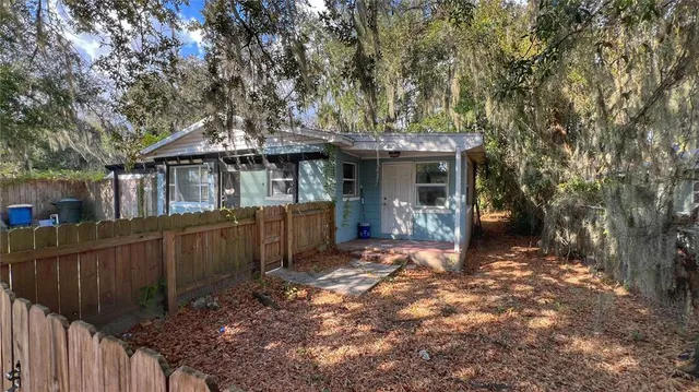 a view of a house with a large tree and wooden fence