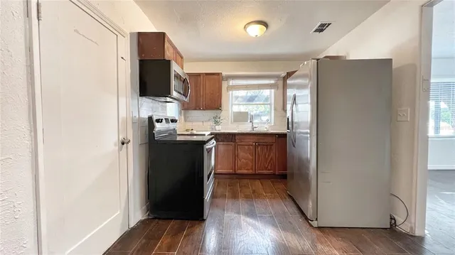 a kitchen with a sink a refrigerator and wooden floor
