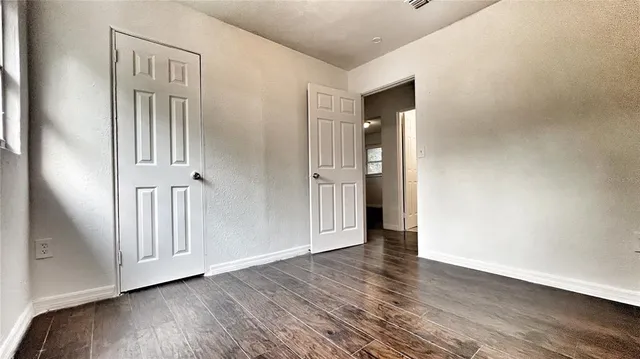 an empty room with wooden floor and entryway