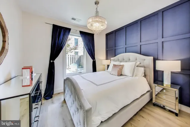 a bedroom with a bed a dresser and potted plants